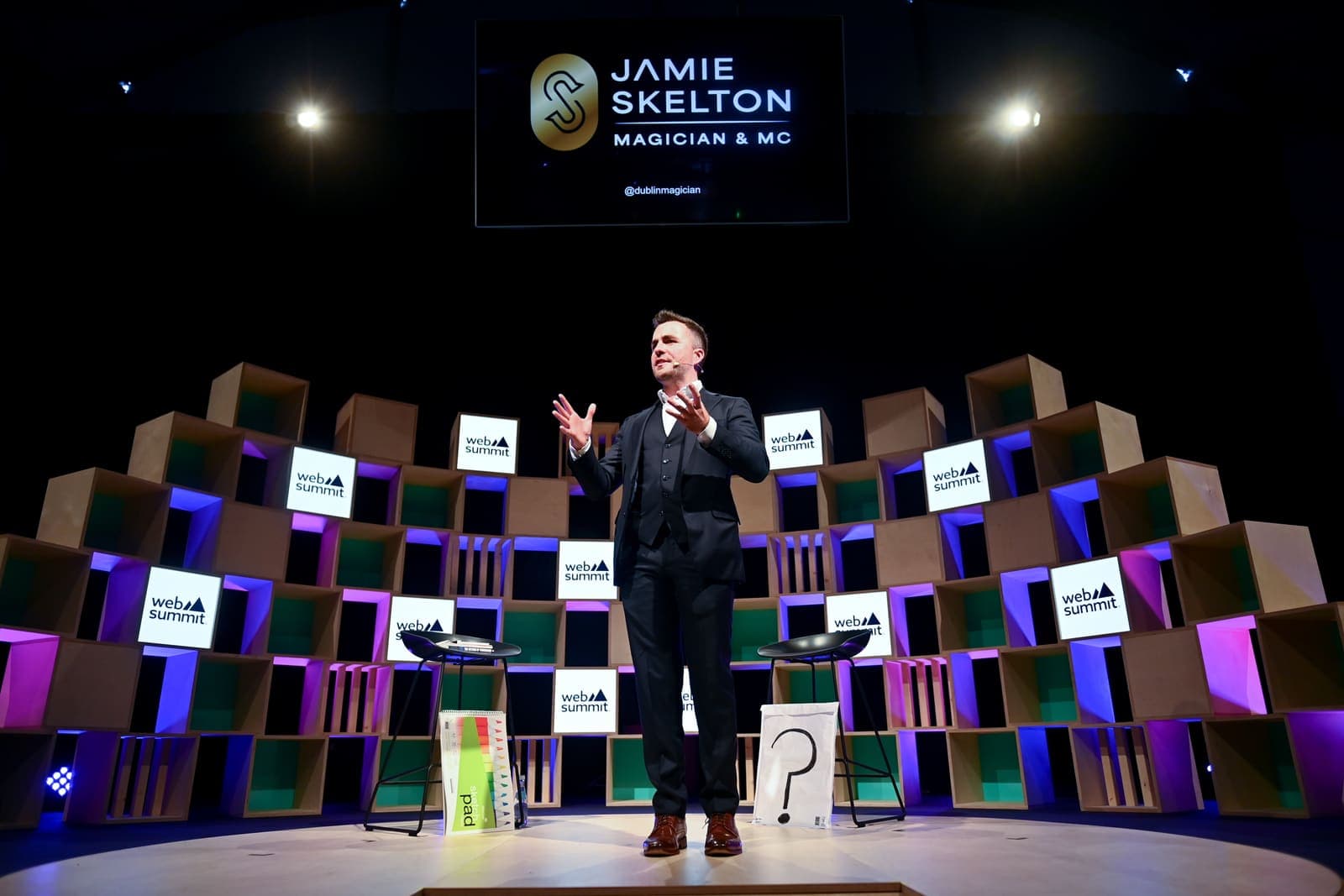 The full Web Summit stage of lit cubes, Jamie in the centre under a screen with his name