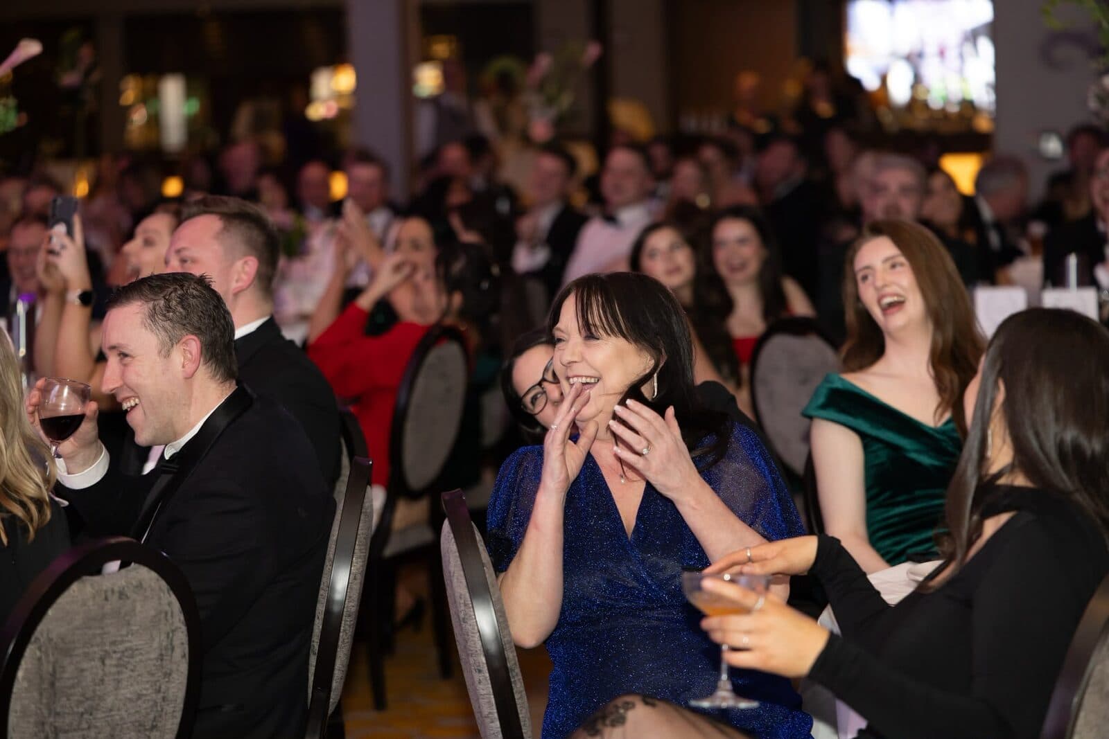 Guests at the weddingsonline Awards 2025 laugh at their tables, one woman in blue with her hands to her face