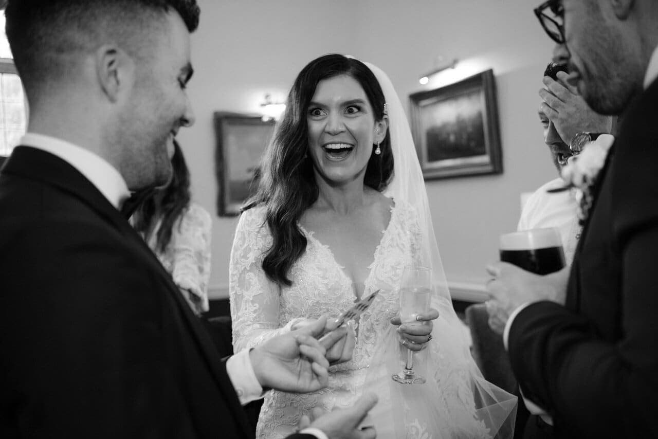 Black-and-white: bride reacts with delight to a card trick