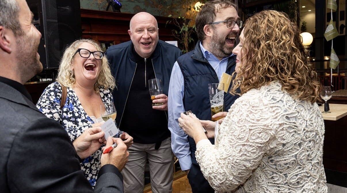 Guests laugh as Jamie does close-up magic at a reception