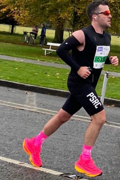 Jamie runs the Dublin Marathon in a black vest, sunglasses and pink running shoes