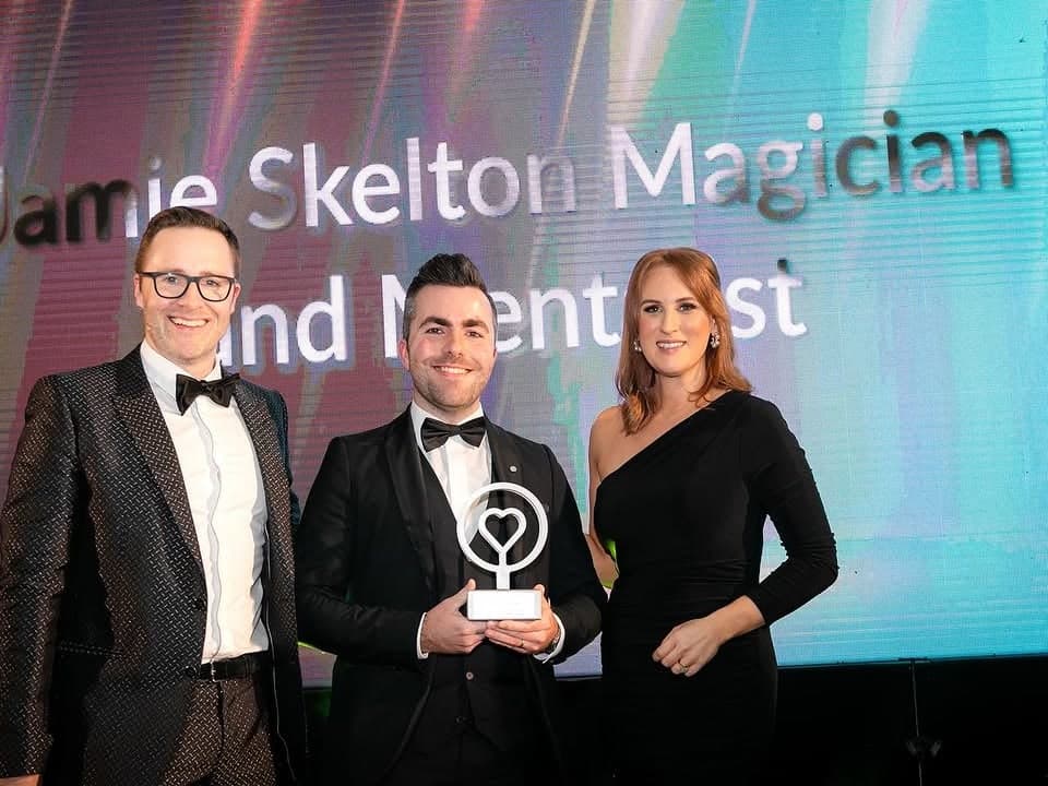 Jamie holds his Magician of the Year trophy on stage beside Keith Barry at the Weddingsuppliers.ie Awards