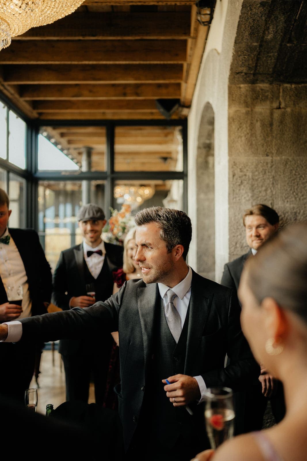 Jamie performs among guests in a stone-walled hall with a wooden ceiling