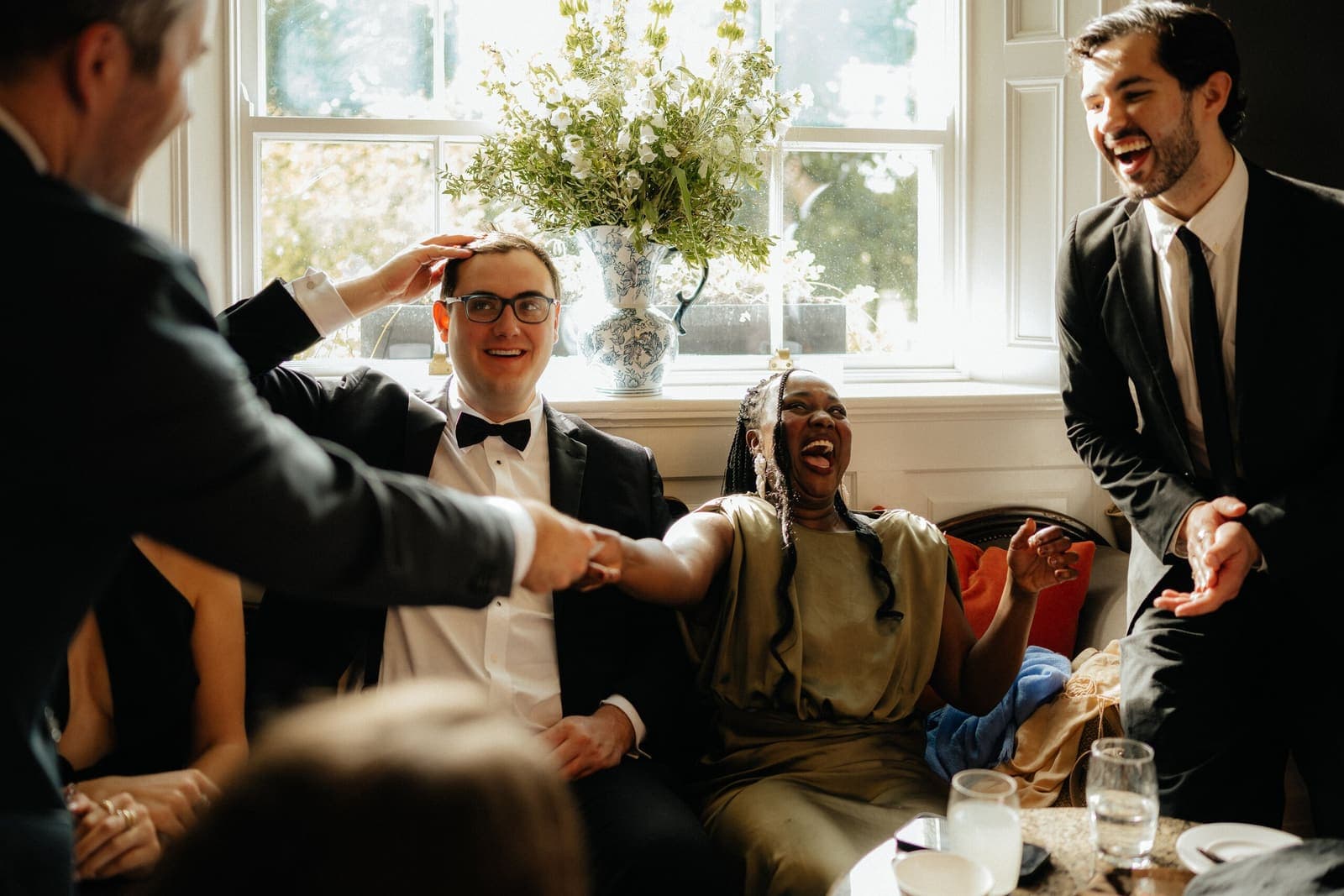 Wedding guests laughing at a trick in a bright sitting room