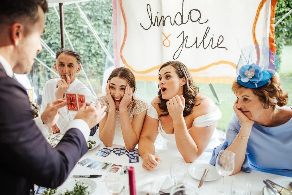Under a banner that reads "Linda & Julie", the two of them gasp and laugh in a marquee as Jamie shows a card