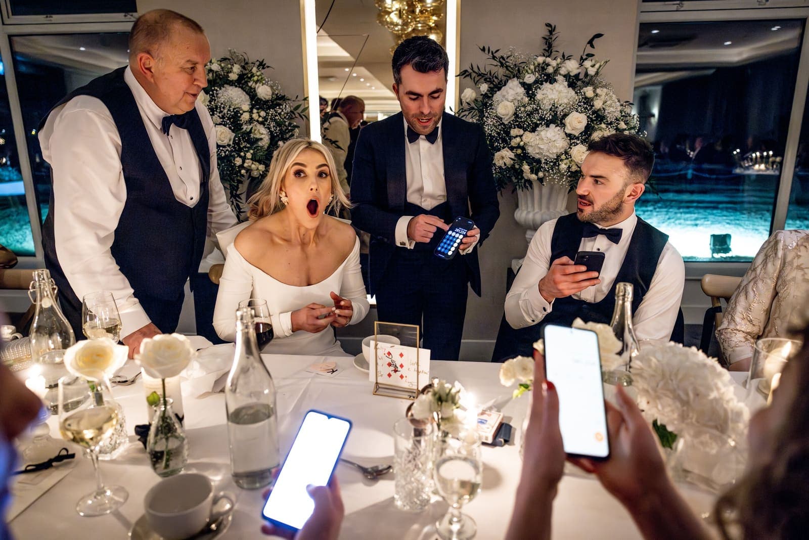 Wedding guests filming on phones as a woman gasps at a trick