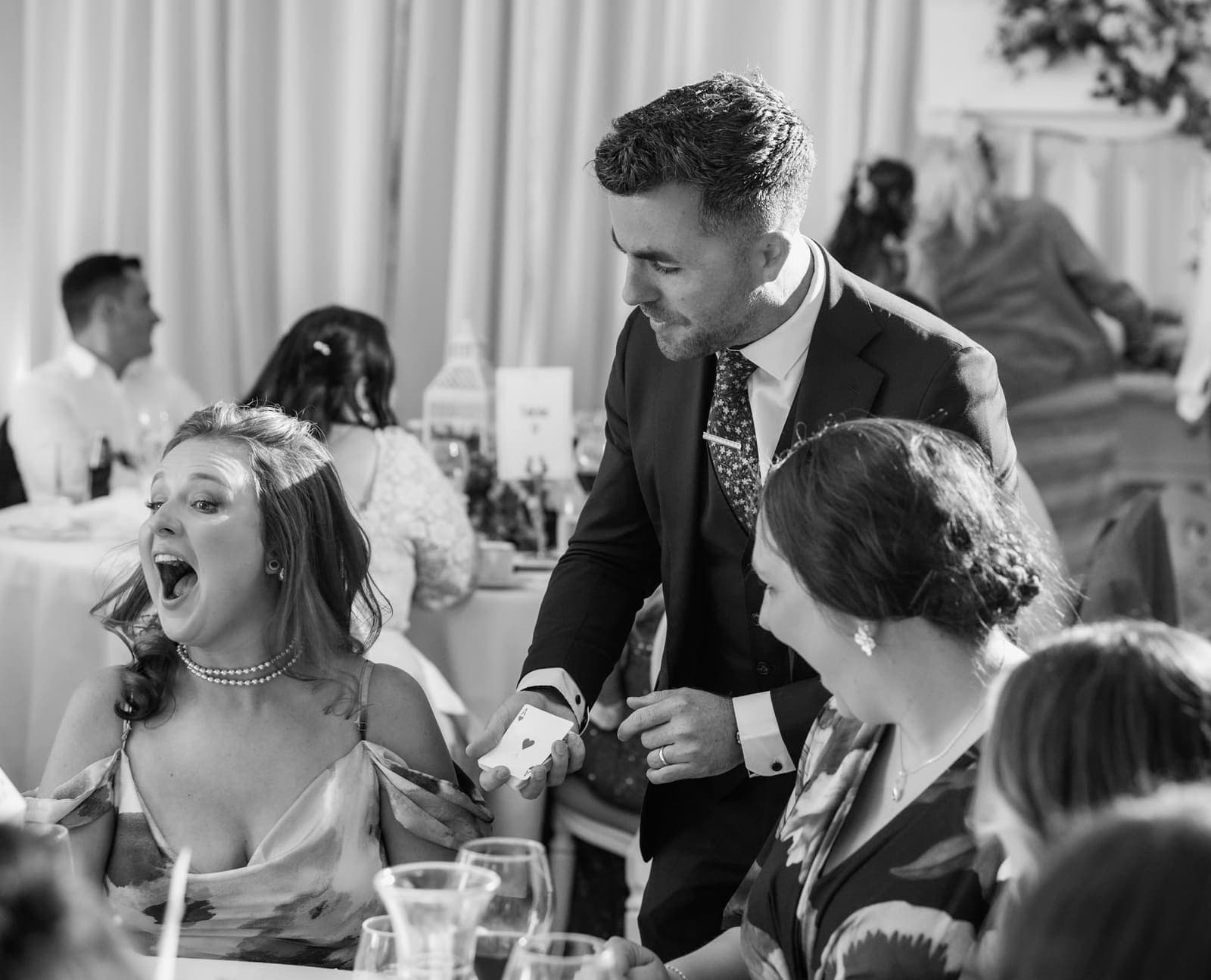 Black-and-white: a guest at a wedding table gasps with her mouth wide open