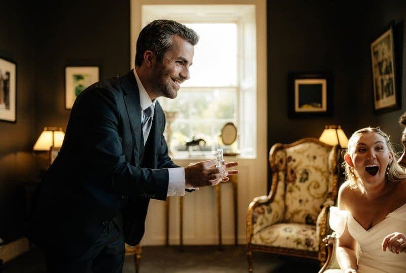 Jamie smiles as a woman in a white dress gasps at his trick, at Shea and Preston's wedding at Clonabreany House