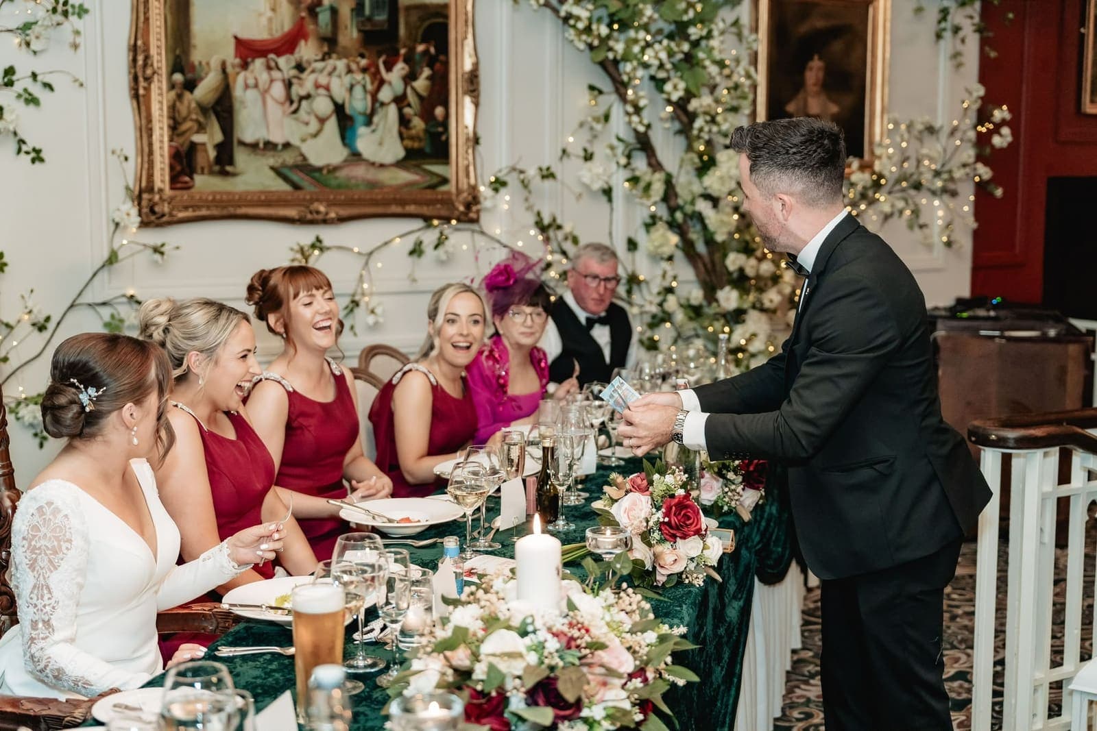 At the same top table, Suzanne and her bridesmaids in red laugh as Jamie does a trick