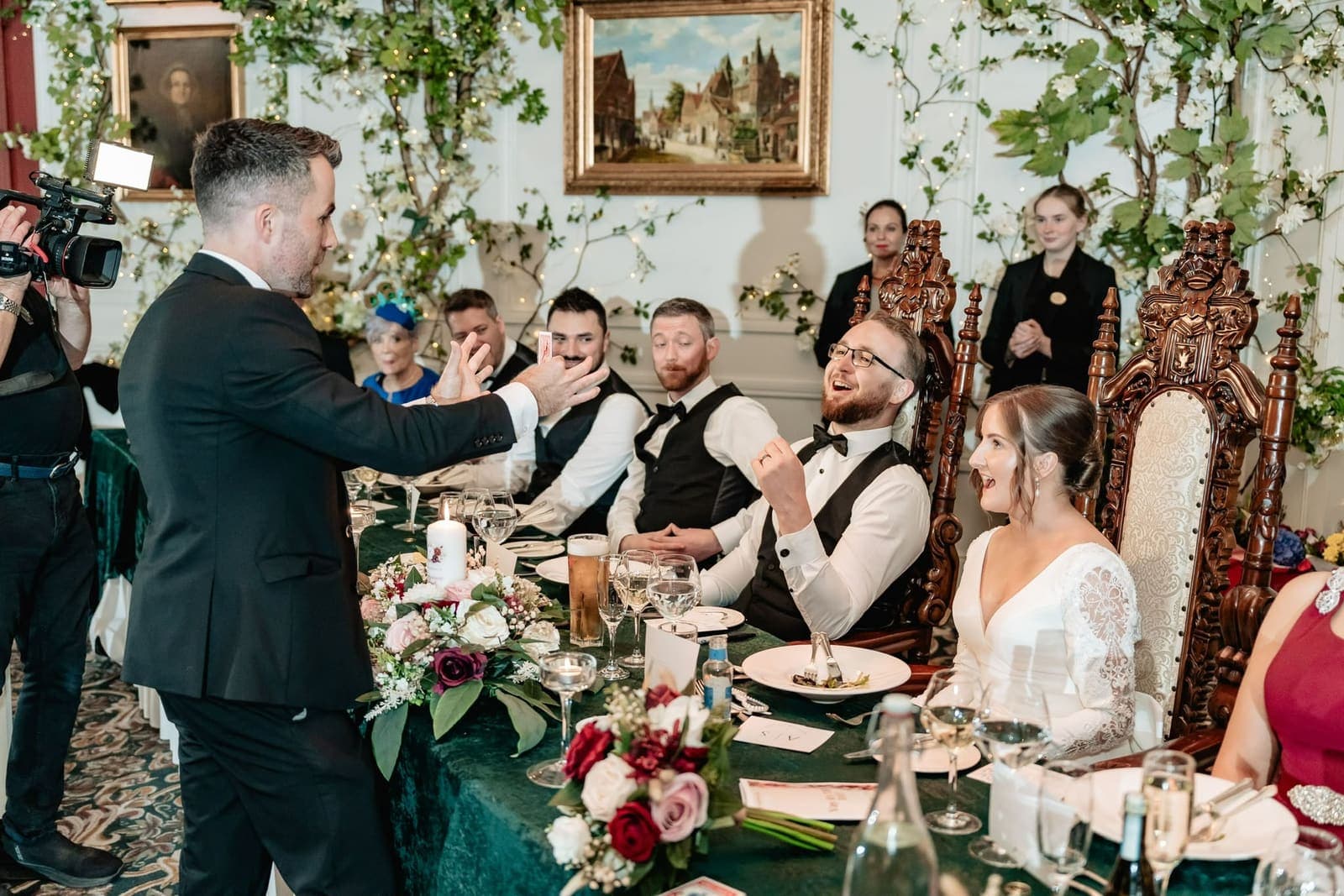 At Alex and Suzanne's top table at Cabra Castle, Alex cheers and Suzanne laughs as Jamie shows a card