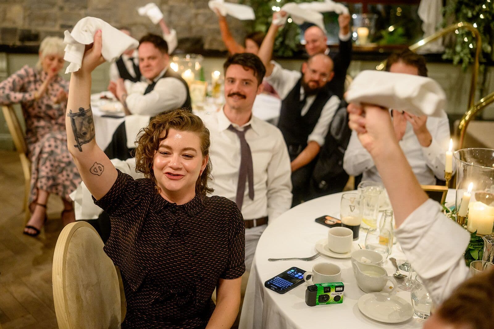 Wedding guests wave white napkins over their heads at their tables