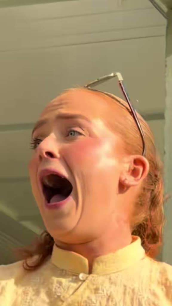 A guest at an outdoor summer function screams with her mouth wide open after a card trick